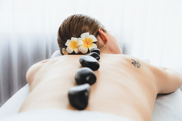 Hot stone massage at spa salon in luxury resort with day light serenity ambient, blissful woman...