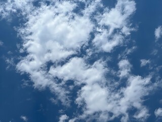 Puffy white cumulus clouds scattered across bright blue sky, creating classic fair weather cloud formation