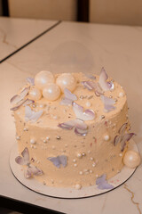 Peach Buttercream Cake with Pearl Accents and Butterfly Decorations, Elegant Dessert Photography, Soft Pastel Colors, Textured Frosting, Celebration Theme.