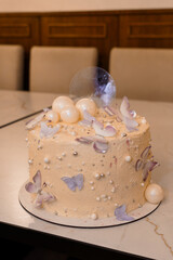 Delicate Peach Butterfly Cake on Marble Table: Elegant Dessert, Pearl Accents, Minimalist Style, Romantic Floral Decoration, Celebration and Sweet Treat.