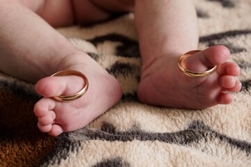 Baby Feet with Wedding Rings, Golden Symbol of Love, New Family, Newborn Toes, Beige Background,...