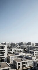 Fototapeta premium A high-angle view of a modern, light gray concrete architectural complex, showcasing numerous uniform buildings with rectangular shapes and repeating window patterns.