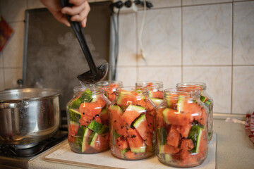 home preservation in the kitchen, boiling water is taken from a saucepan with a ladle and poured...