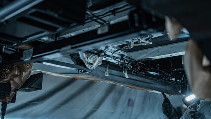 Automotive technician applying rustproof protective coating under a vehicle. Process helps prevent...