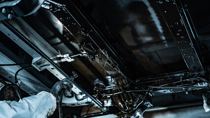 Automotive technician applying rustproof protective coating under a vehicle. Process helps prevent...