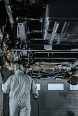 Fototapeta premium Automotive technician applying rustproof protective coating under a vehicle. Process helps prevent corrosion and extend vehicle lifespan. Ideal for illustrating car maintenance, vehicle care.