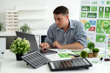 Business professional analyzing environmental sustainability reports developing green energy strategy modern office workspace