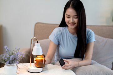 Woman enjoys cozy home ambiance using modern candle warmer with scented natural aroma for relaxation comfort and peaceful atmosphere