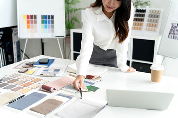 Professional woman designer evaluates sustainable material samples for eco friendly interior project modern office