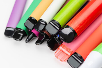 Colorful disposable vapes arranged close-up, modern electronic smoking devices in various bright...