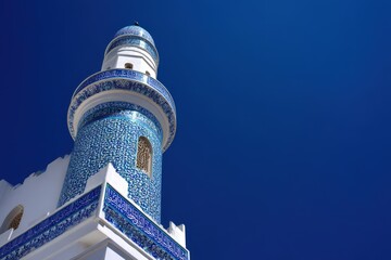 Beautifully decorated mosque minaret with intricate blue tilework and Islamic architecture, standing tall under a vivid, cloudless sky.