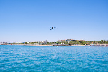 Drone flying above the sea, showing a resort hotel beach with a pier and sun loungers. Summer...