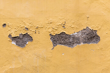 Gelbe Wand oder Mauer mit abgeplatztem beschädigtem Putz