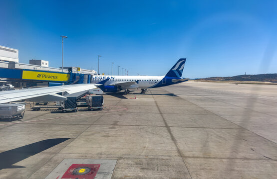 Chania, Greece. Aegean Airlines plane parked at the gate of Chania International Airport, ground service vehicles on the tarmac