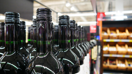 Close-up of many gloss black bottle of wine standing on a retail display