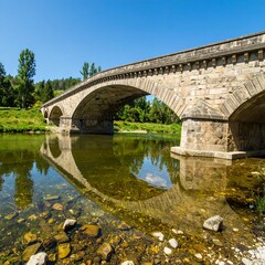 Fototapeta premium Stone arch bridge over a calm river