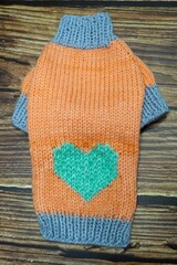 top view of knitted orange dog sweater with mint heart and gray rib. warm pet clothes. cozy