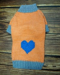 top view of knitted orange dog sweater with blue heart and gray rib. warm clothes for pets