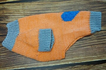 side view of knitted orange dog sweater with blue heart and gray rib. warm pet clothes