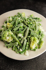 Frozen green vegetables green peas, broccoli, string beans, kohlrabi kale tasty snack fresh food background on the table rustic food top view copy space keto and paleo diet vegan and vegetarian food