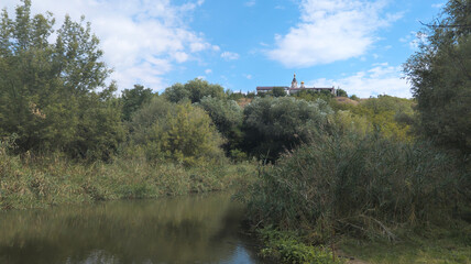 Kosmodemyanskaya Church towering over lush vegetation and calm river