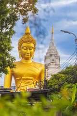A large seated Buddha or Buddha Dhammakaya Dhepmongkol at Paknam Phasi Charoen temple on a blue sky day.