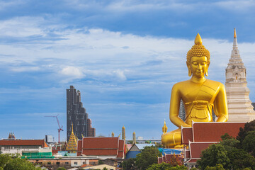 A large seated Buddha or Buddha Dhammakaya Dhepmongkol at Paknam Phasi Charoen temple on a blue sky day.