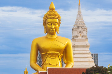 A large seated Buddha or Buddha Dhammakaya Dhepmongkol at Paknam Phasi Charoen temple on a blue sky day.