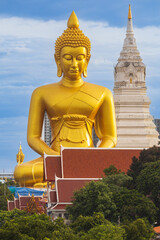 A large seated Buddha or Buddha Dhammakaya Dhepmongkol at Paknam Phasi Charoen temple on a blue sky day.