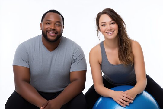Smiling caucasian female and african male adults with fitness ball on white background
