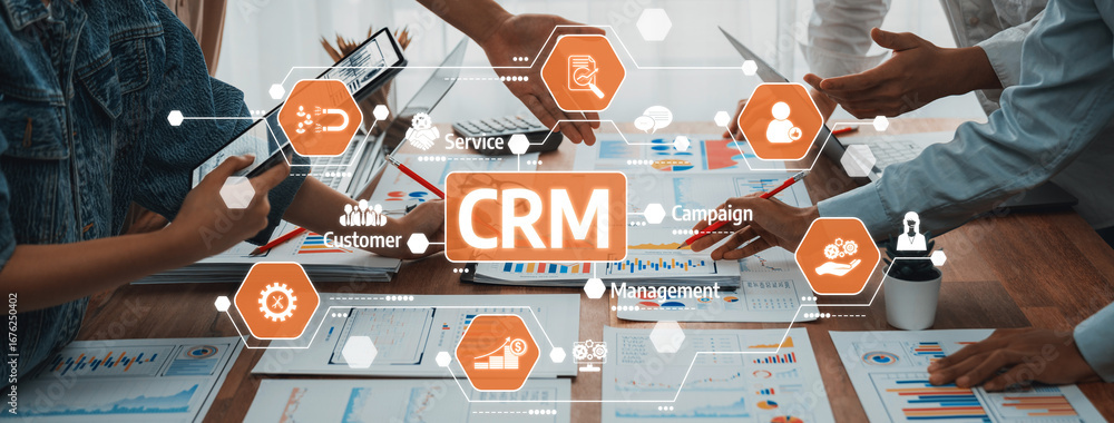 Poster This image captures a collaborative business atmosphere with hands engaging over charts and devices while discussing CRM strategies for enhanced management and customer insights. Amity