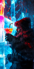 Man in a fur coat holding a colorful cocktail, standing against an icy backdrop illuminated with vibrant blue and pink lights, showcasing a unique winter experience