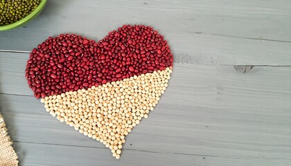 Heart-shaped design made of red and white beans on a gray wooden surface