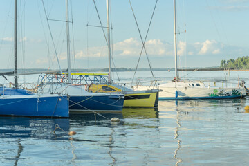 Fototapeta premium Sailboats docked at quiet marina under clear blue sky. Yachts moored quietly in the harbor, poised for new journeys beneath an endless sky of freedom and possibility.