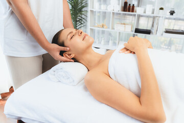 Fototapeta premium Caucasian woman enjoying relaxing anti-stress head massage and pampering facial beauty skin recreation leisure in dayspa modern light ambient at luxury resort or hotel spa salon. Quiescent