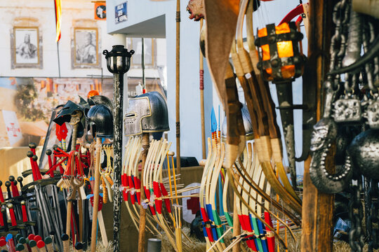 Toy swords, helmets, bows, and maces are showcased for sale at a medieval festival market in Castro Marim.