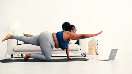 Black woman trains core with extended arm and leg balance