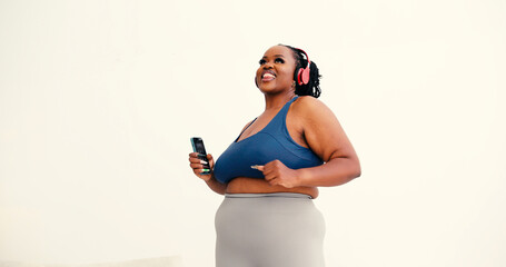 Confident black woman in athletic wear dances listening to music