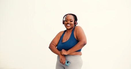 Confident black woman in athletic wear dances listening to music