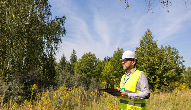 Male forestry inspector studying the condition of trees in the forest. Work Ecologist. Eco control. Conducting environmental monitoring.	
 - Powered by Adobe