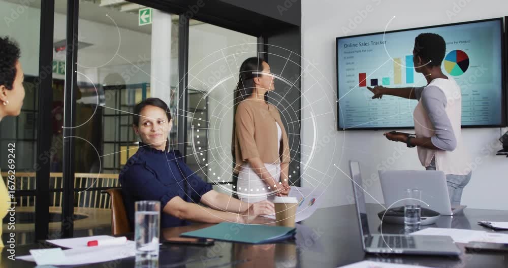 Poster presenter tapping tablet and highlighting sales bar, pie charts in meeting while team taking notes