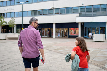 Father and daughter talking and walking in town centre. shopping.