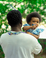 Father with his daughter in nature wearing white clothes and Afro-Brazilian religious accessories....