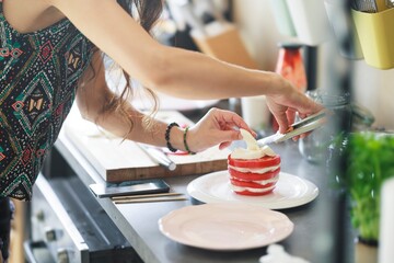 In a bright kitchen, a woman meticulously crafts a caprese salad tower. Alternating slices of ripe...