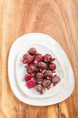 Freshly picked beets, still showing some soil, rest on a simple white plate. The scene is set against a warm, wooden background. The beets are ripe and ready to be prepared