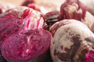 Cut and whole beetroots cluster, their rich purple flesh exposed. Some are covered in a pale,...