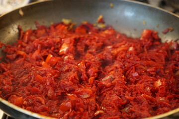 Sauté for borscht made of beets, onions, bell pepper, and carrots in a frying pan.
