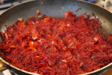 Sauté for borscht made of beets, onions, bell pepper, and carrots in a frying pan.