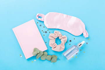 Sleeping mask with accessories on color background, top view. Sleeping routine concept