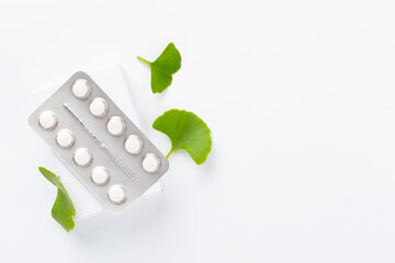 Ginkgo leaf with bottle of pills on color background, top view